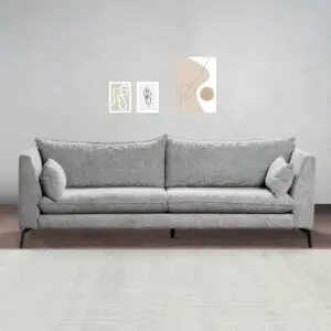 סלון מודרני כולל את הספה האפורה VINA עם שתי כריות תואמות על קיר אפור בהיר. שלוש יצירות קו מינימליסטי תלויות מעל הספה, ושטיח בעל מרקם בהיר מכסה את הרצפה.