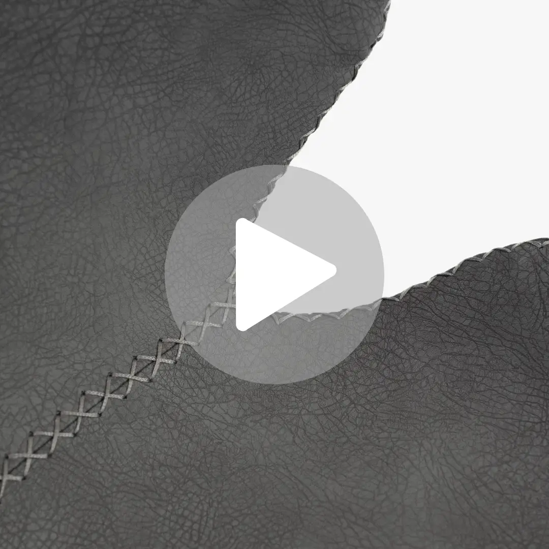 תקריב של סמל לחצן הפעלה חוזר על גבי משטח עור אפור בעל מרקם המזכיר את ALEX. התפירה הנראית לעין והמראה הסדוק יוצרים מראה מופשט ומחוספס עם גוונים משתנים של אפור.