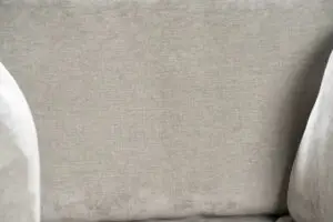 תקריב של ARM CHAIR SAND, הכולל ריפוד בד אפור בהיר עם גימור מרקם בגב ובמשענת היד. הבד נראה רך וחלק, משרה נוחות ונעימות.