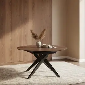 שולחן עץ עגול START עם רגליים שחורות מוצלבות ניצב על שטיח בהיר עם דוגמה, ועליו אגרטלים ניטרליים ועשבים יבשים, היוצרים פינת אוכל יוקרתית על רקע קירות עץ בהירים בסביבה מינימליסטית.
