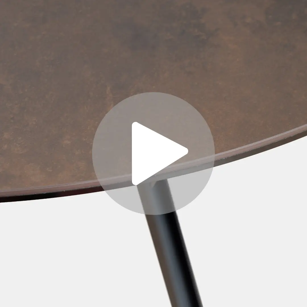 תקריב של השולחן העגול START הכולל משטח בעל מרקם חום המשרה אלגנטיות של פינת אוכל יוקרתית. הוא עומד על שלוש רגליים שחורות, עם שכבת על של כפתור הפעלה במרכז.