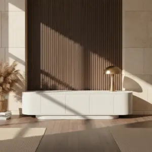 חלל מגורים מודרני מציג את מזנון הטלוויזיה הלבן FOX, בליווי מנורת כיפה מוזהבת וקישוט מעשב פמפס. אור השמש יוצר צללים על קיר האריחים הבז' ועל רקע לוחות העץ האנכיים.