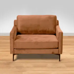 כורסת ARM CHAIR MAMBA, כורסה רחבה ומפנקת מבד קטיפה חום עם משענות יד דקיקות ורגלי מתכת, ניצבת על רצפת עץ בהירה על רקע קיר אפור בהיר.