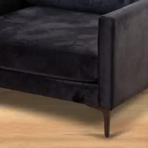תקריב של ARM CHAIR MAMBA, כורסת רביצה מוזהבת עם רגליים מתכתיות דקיקות, המונחת על רצפת עץ בהירה.