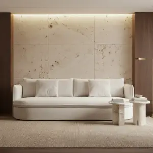 סלון מודרני עם ספה CIRI יוקרה לבנה, שלוש כריות לבנות, שני שולחנות צד עגולים משיש, שטיח בז' וקיר אבן גדול המוקף בלוחות עץ.